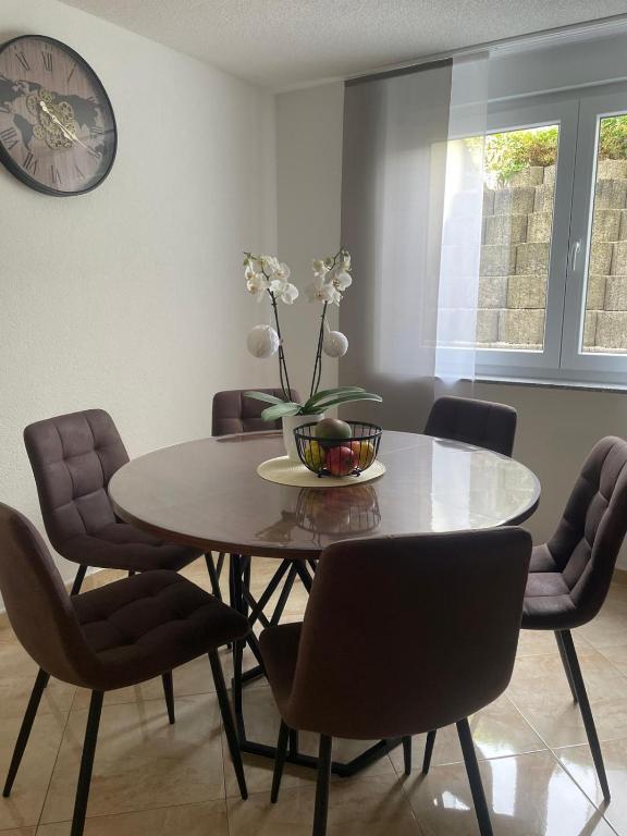 a dining room with a table with chairs and a clock at Mng home in Kippenheim