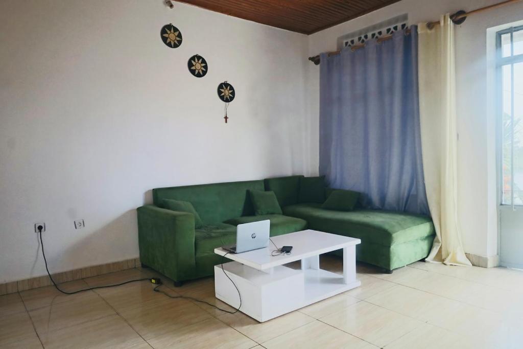 a living room with a green couch and a laptop on a table at Chez Kivu in Rubavu