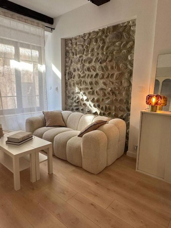 a living room with a couch and a stone wall at Le Petit Palais, en hyper centre de Valence in Valence