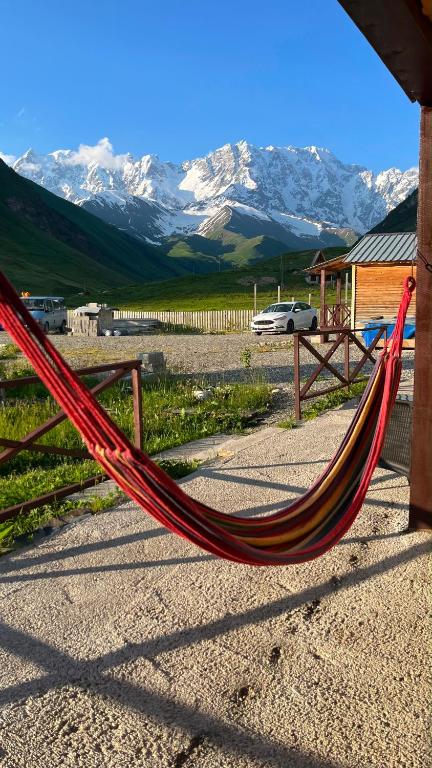 a red hammock with mountains in the background at LEMI Mountain Cottages - Ushguli in Ushguli