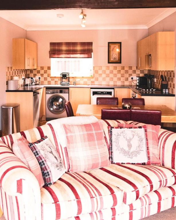 a living room with a couch and a kitchen at Ardbrae Cottage in Daviot