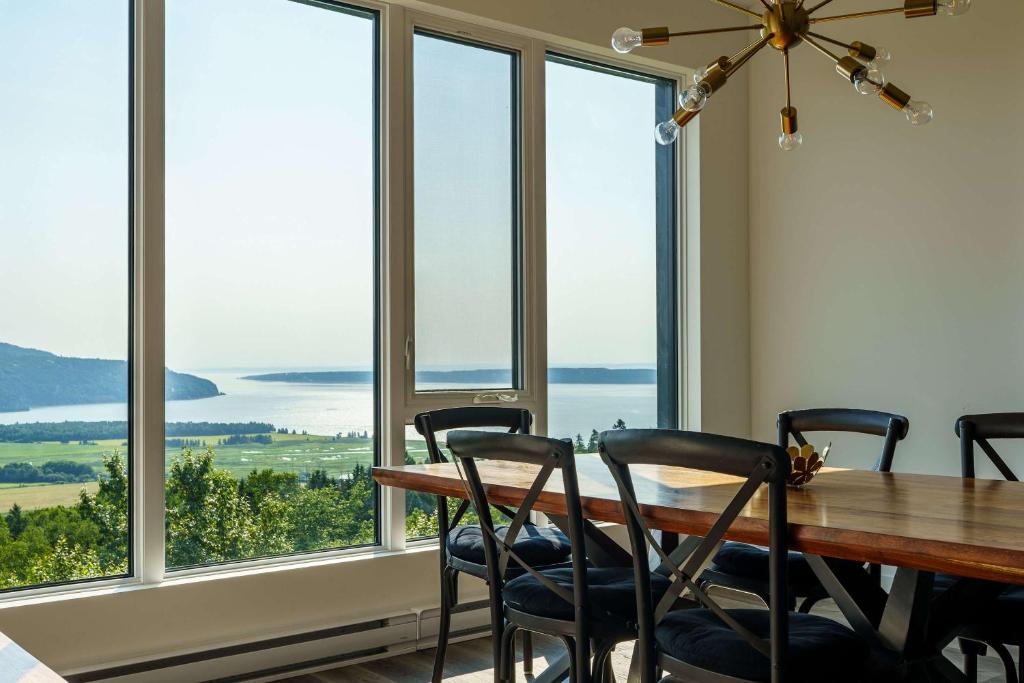 a dining room with a table and chairs and large windows at Luxury Coffee Bean Condo - Pool & Stunning View in Baie-Saint-Paul