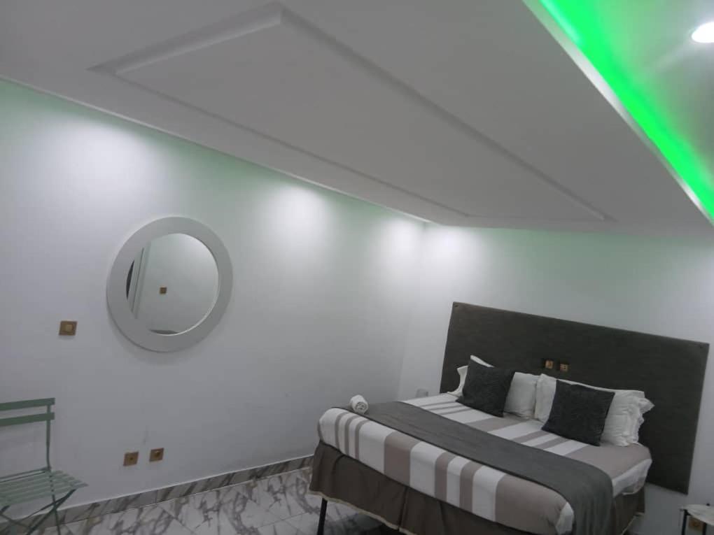 a white bedroom with a bed and a mirror at Immobilier Du siecle in Abidjan