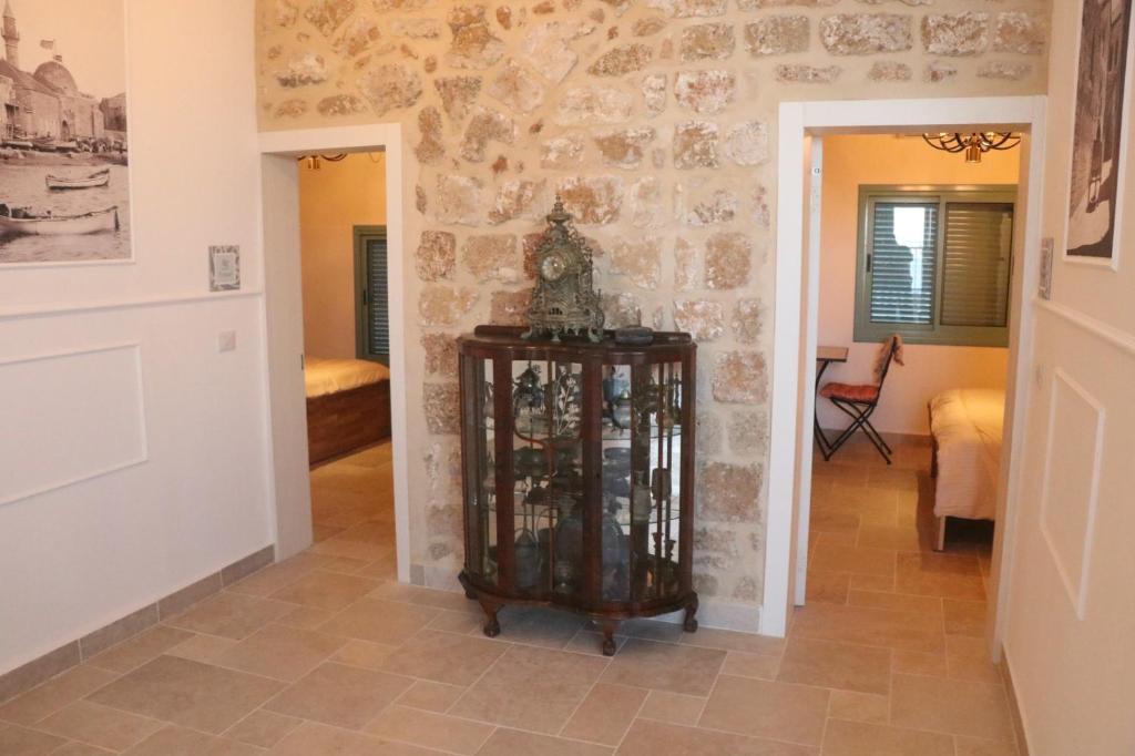 a room with a stone wall and a clock on a table at Ayham dream house in Acre