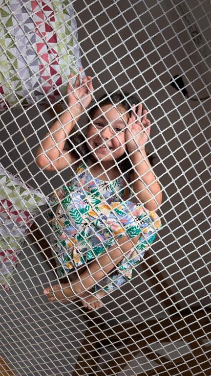 a child is sitting in a metal cage at Gites Les Cordées Liées - clim & parking centre ville in Albi