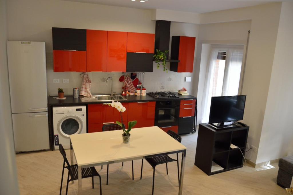 ローマにあるApartment Veioのキッチン(オレンジ色のキャビネット、テーブル、椅子付)
