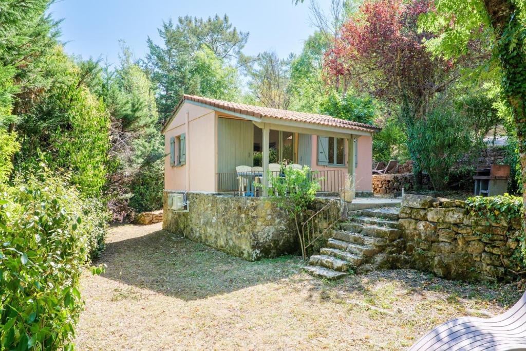 a small house with a stone wall at Chalet confort 4 piscine partagée in Les Vans