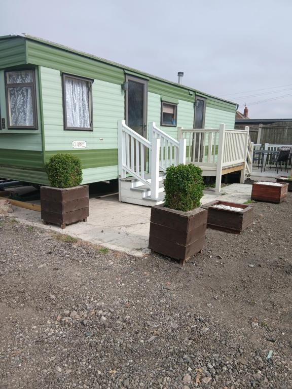 a green trailer with a porch and two bushes at Hillcrest hideaways2 in Hunmanby