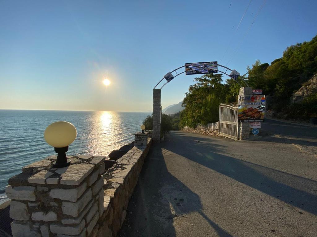 a stone wall next to a body of water at Hotel Brigeni & Camping Riviera in Shëngjin