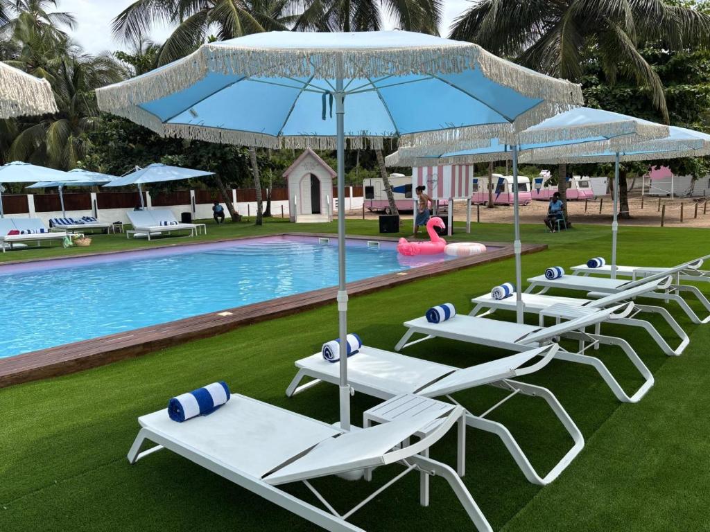 a group of lounge chairs and umbrellas next to a pool at Roulotte Beach São Tomé in Triunfo