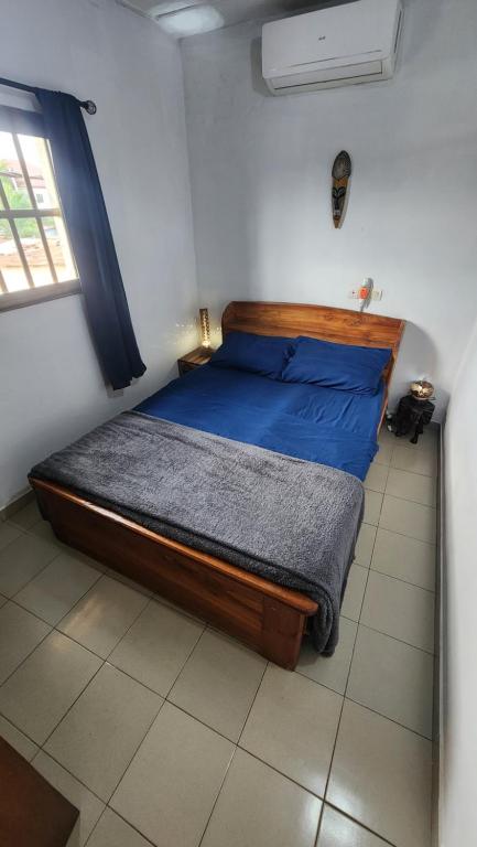 a bedroom with a bed with blue sheets and a window at Le perchoir bleu in Lomé