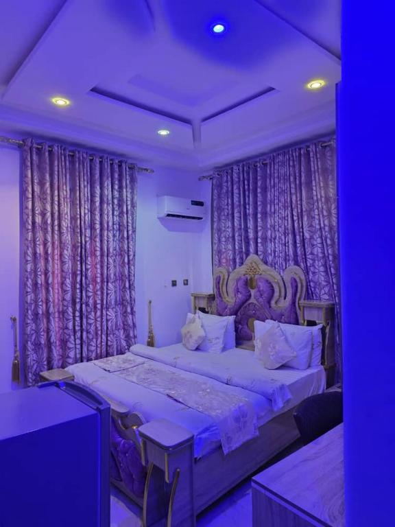 a bedroom with a large bed with purple curtains at Single Room in Abuja
