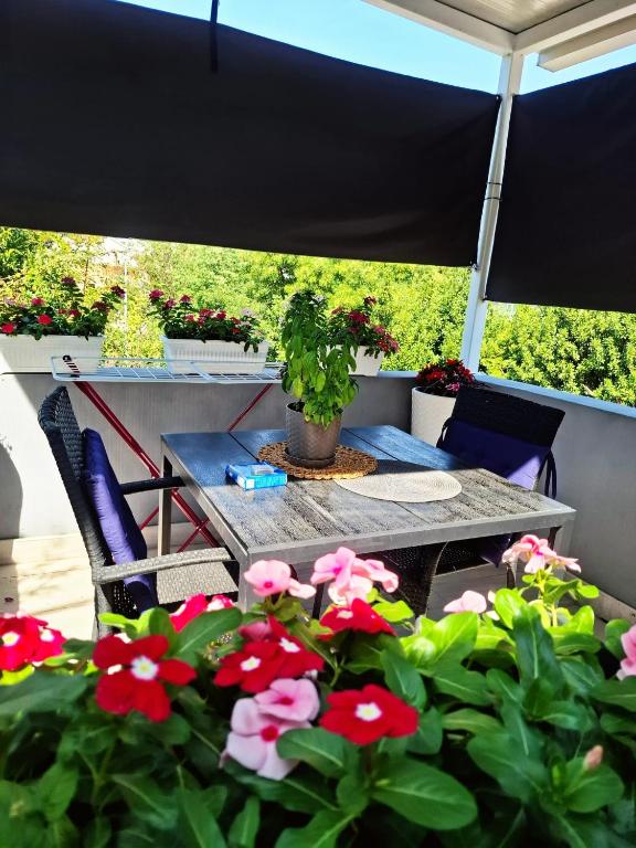a table and chairs and flowers on a patio at Apartman Jadranka in Rogotin
