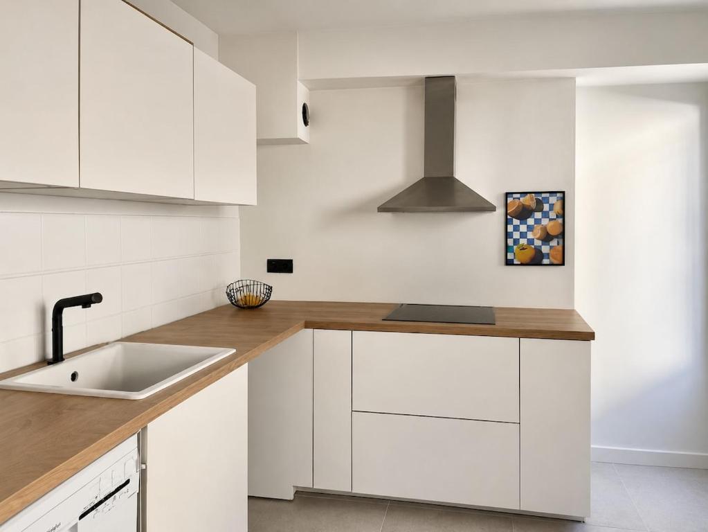a kitchen with white cabinets and a sink at Cocon hyper centre de Pau avec parking in Pau