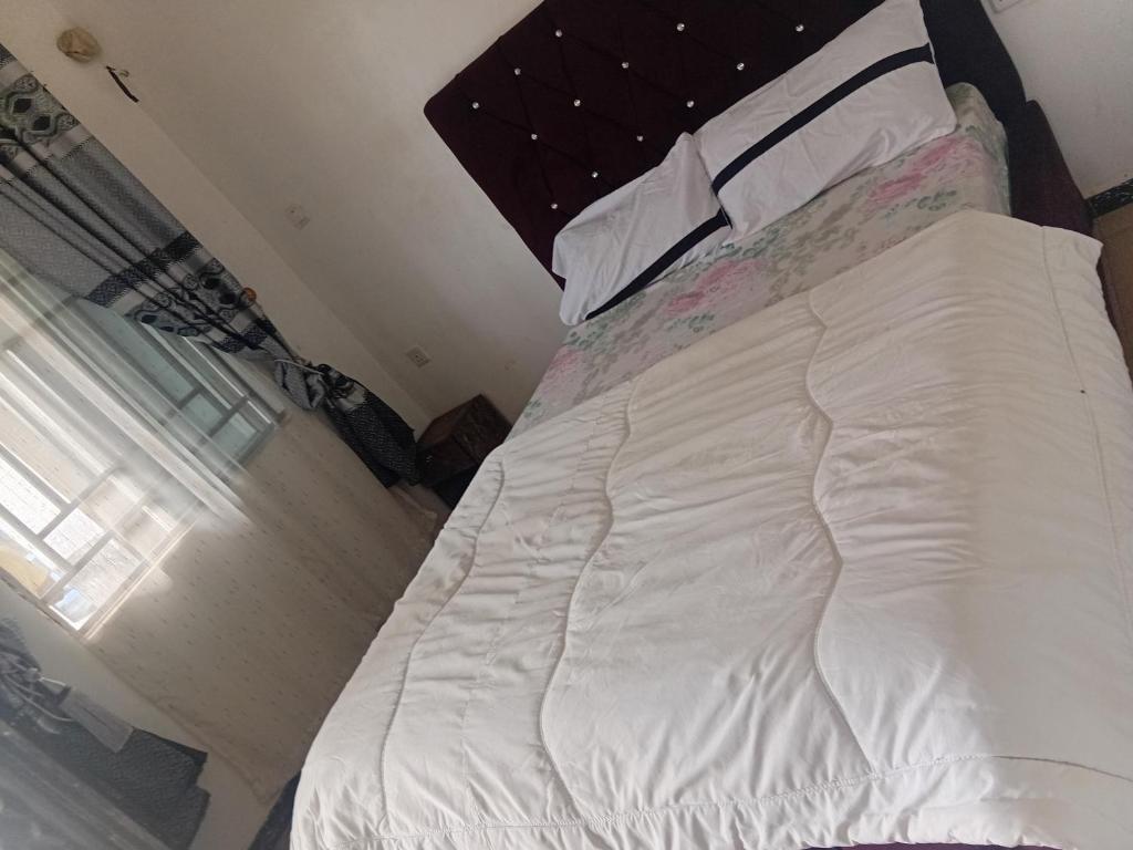 a large white bed in a bedroom with a window at Kings Hotel and Lounge in Bwari