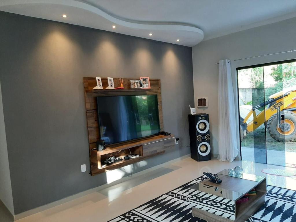 a living room with a flat screen tv and a table at Sitio ALI in Cachoeira Paulista