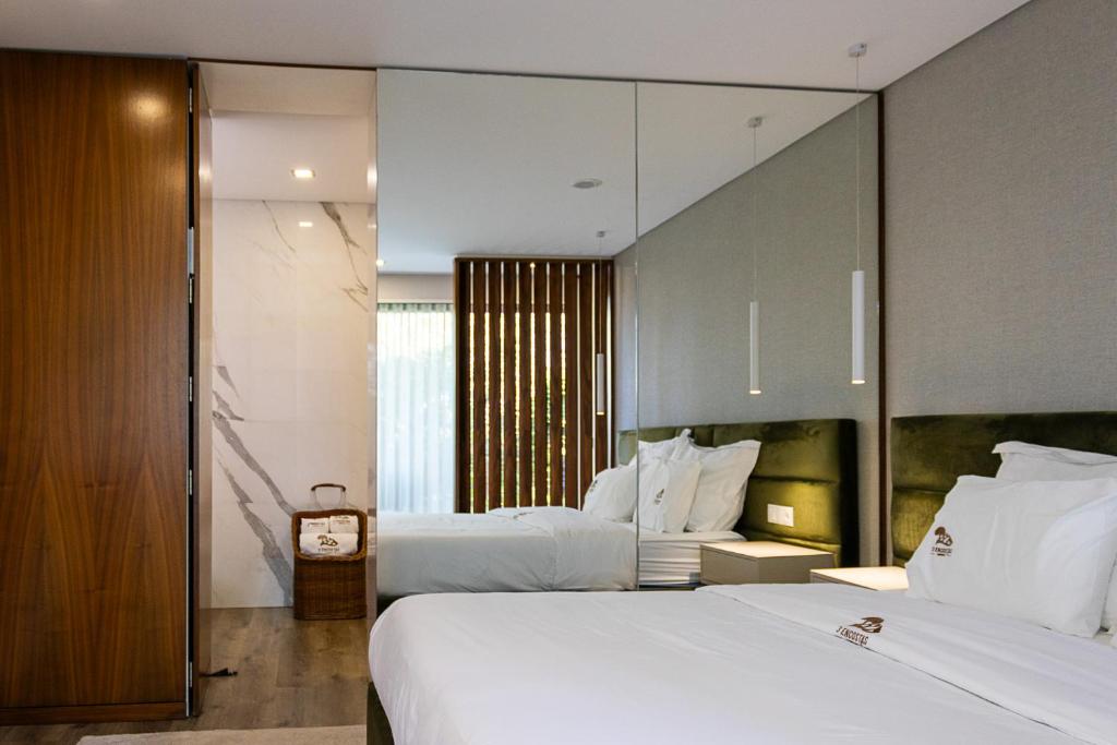 a hotel room with two beds and a mirror at 3Encostas in Cabeceiras de Basto