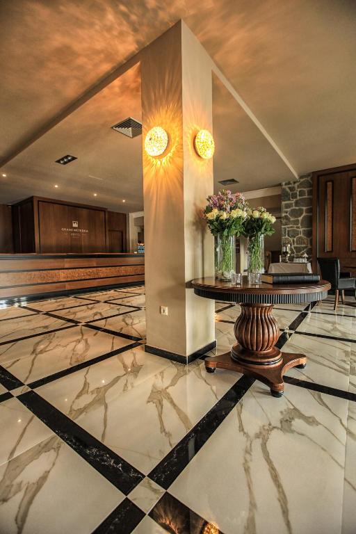 a lobby with a table with flowers on it at Grand Meteora Hotel in Kalabaka