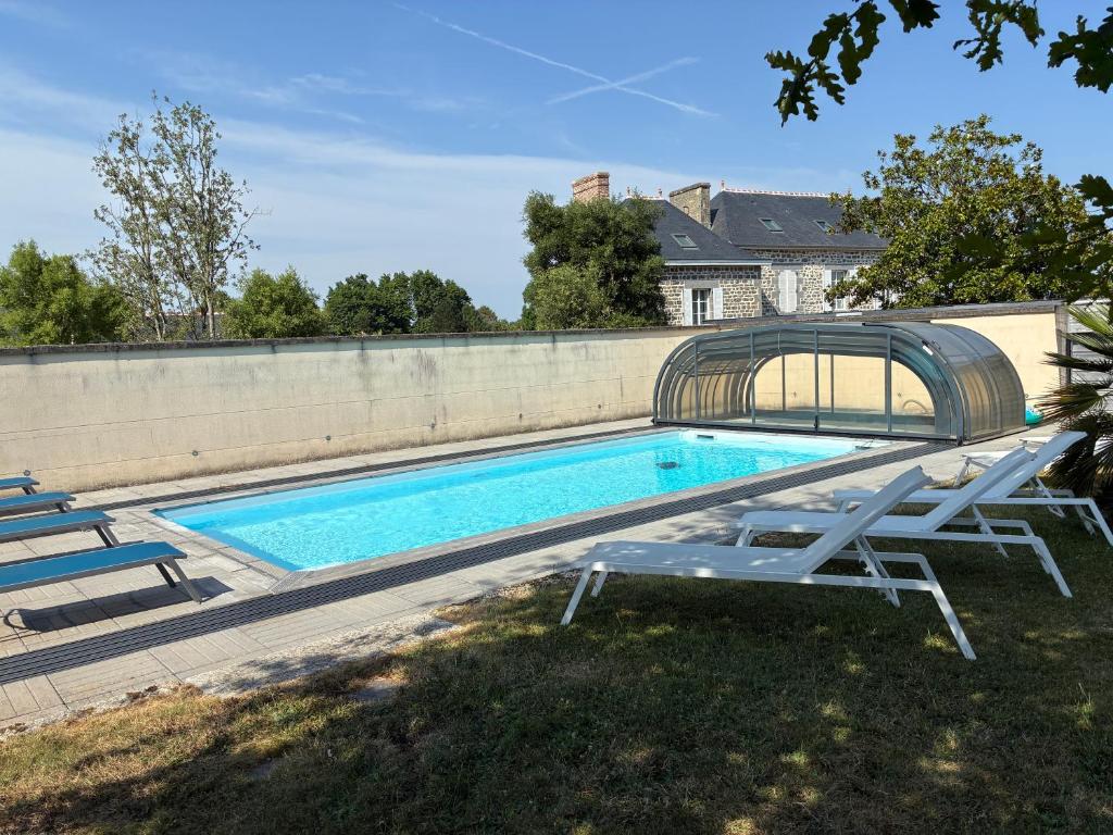 a swimming pool with two lounge chairs next to a wall at Domaine Les Jardins dArsene in Tinténiac