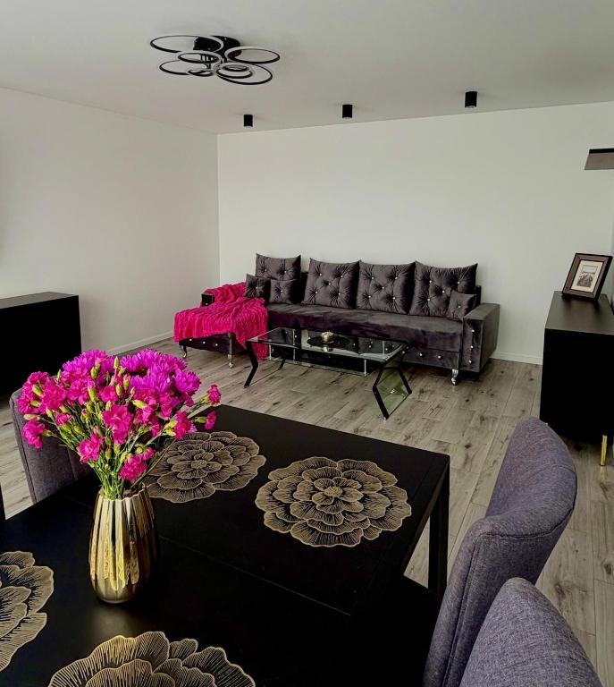 a living room with a couch and a table with purple flowers at Silver II in Świnoujście