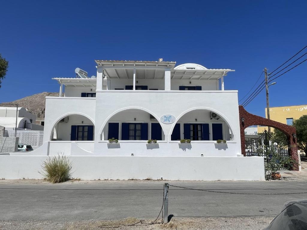 a white house with blue shutters on a street at Villa Nefeli in Perissa