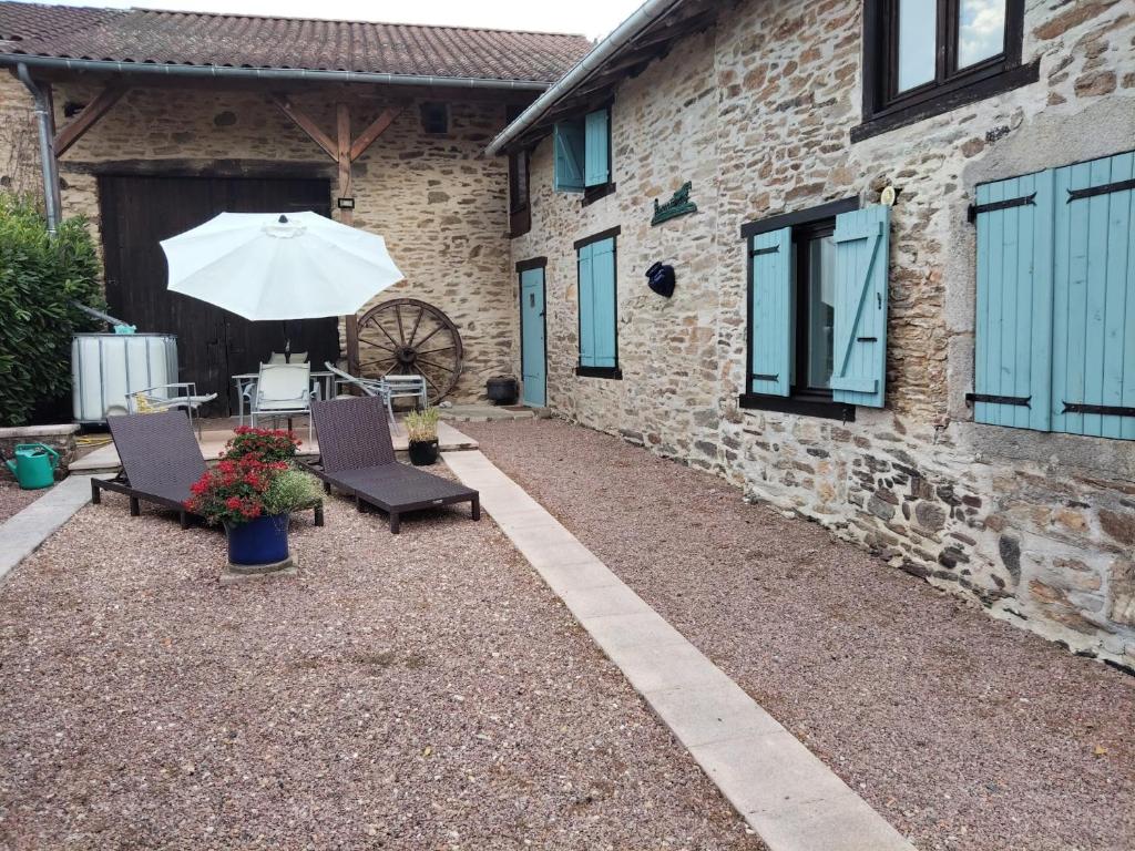 a patio with chairs and an umbrella next to a building at Kinvara Gite in Dournazac