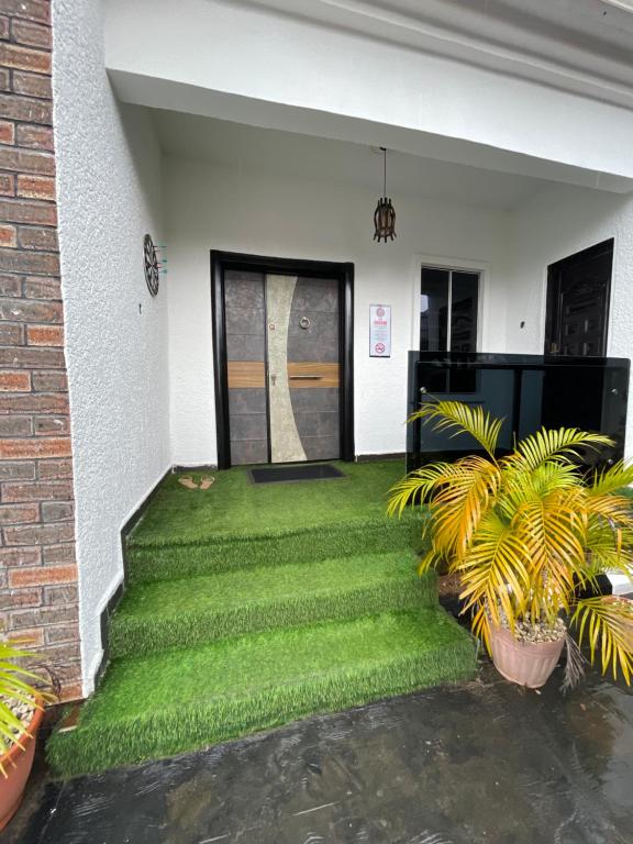 a house with a green lawn in front of a door at At Kora Apartment and Shortlets in Asaba