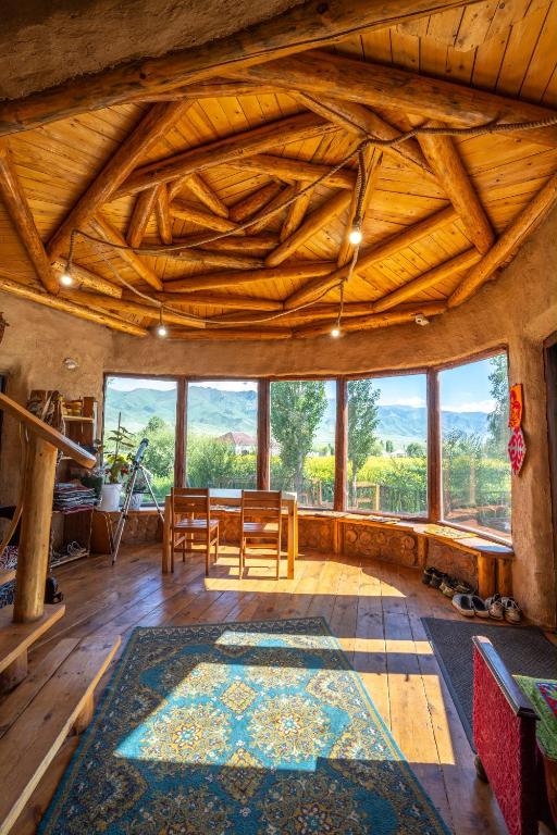 a living room with a table and chairs and windows at KyzArt Hotel & Horse Tours in Bagysh