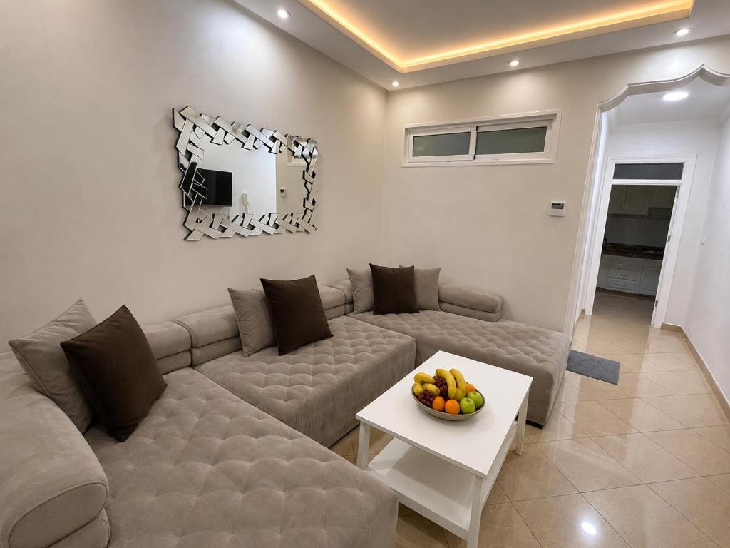 a living room with a couch and a table with a bowl of fruit at Royal Rif Alhoceima Centre in Al Hoceïma