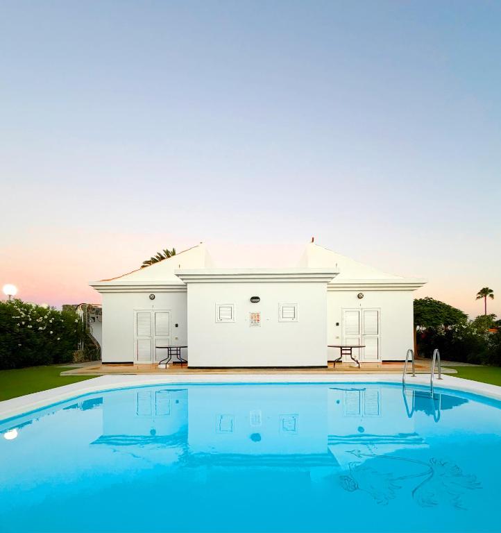 a large swimming pool in front of a white house at Bungalows Las Almenas in Maspalomas
