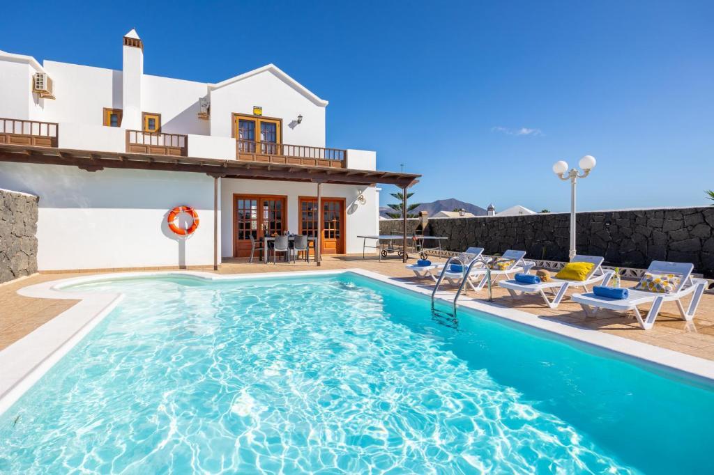 a villa with a swimming pool in front of a house at Villa Alexsandra in Playa Blanca