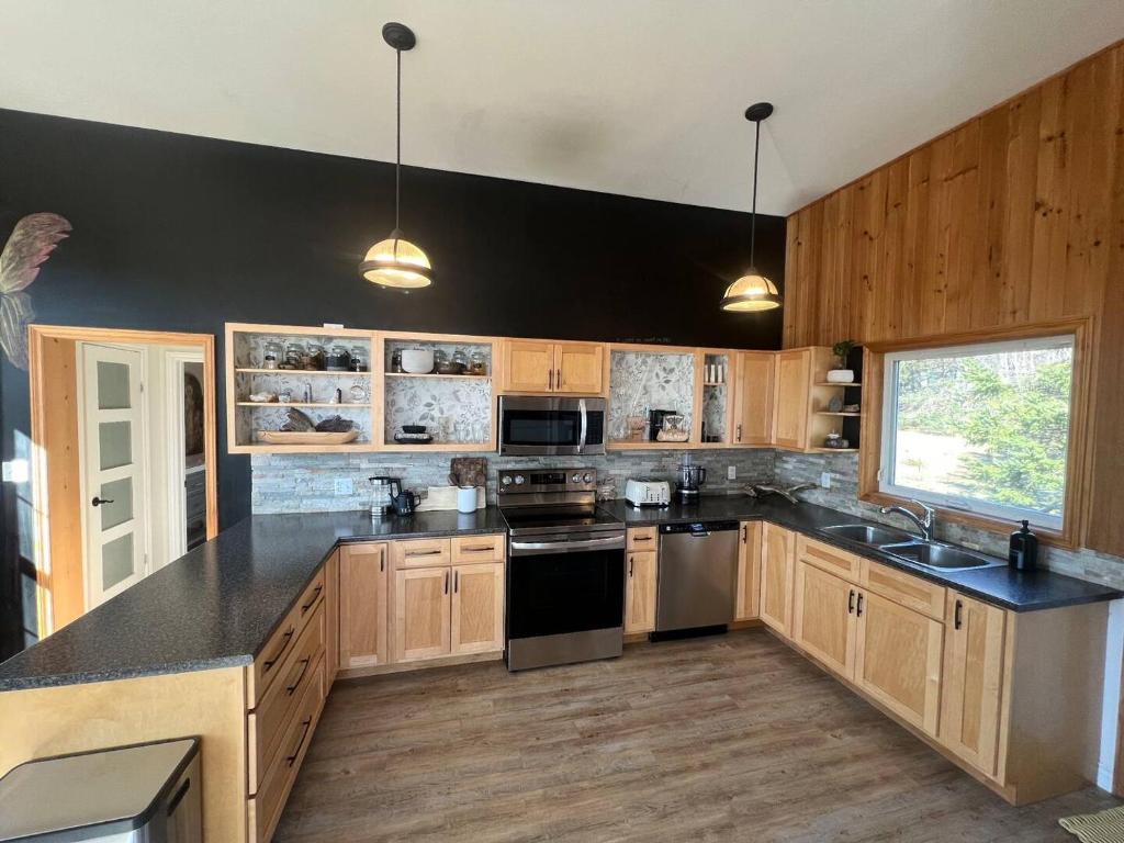 a large kitchen with wooden cabinets and black counter tops at Brackley Beach Schoolhouse in Brackley Beach