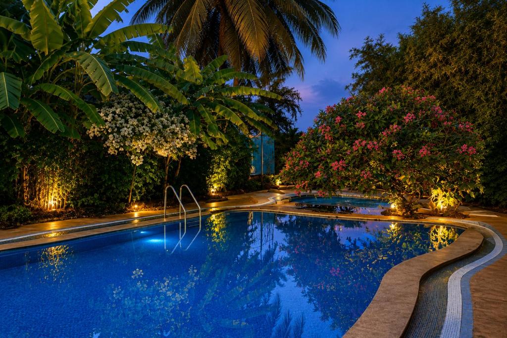 a swimming pool in a garden at night at Cavala The Seaside Resort, Baga in Baga