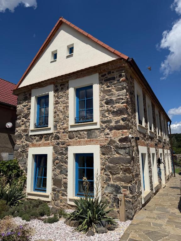 a stone house with white windows on the side of it at ŠTAJNHAUS DUBICE in Řehlovice