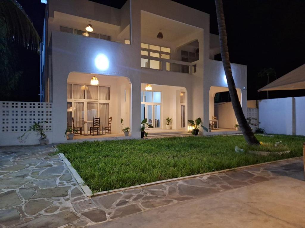 a large white house with a yard at night at Lilo House in Watamu