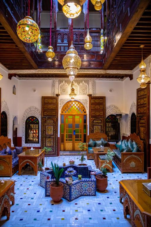 ein Wohnzimmer mit Sofas, Tischen und Kronleuchtern in der Unterkunft RIAD HIKAYA - Born of History in Fès