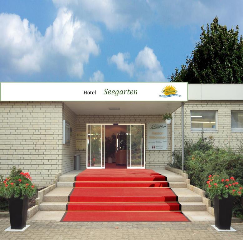 eine mit rotem Teppich ausgelegte Treppe, die zu einer Hotelrezeption führt in der Unterkunft Hotel Seegarten Quickborn in Quickborn
