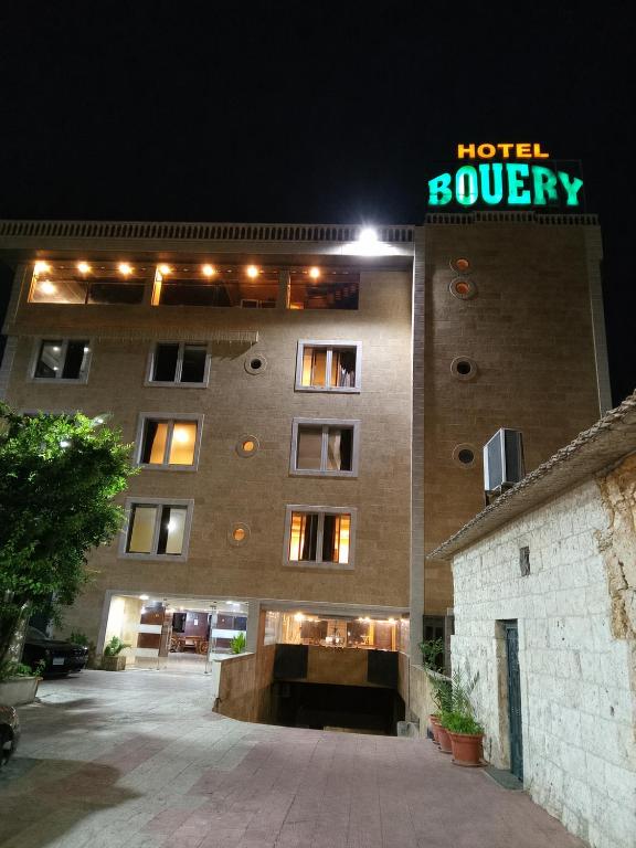 a building with a hotel survey sign on it at night at Hotel Bouery in An Nā‘ūrah