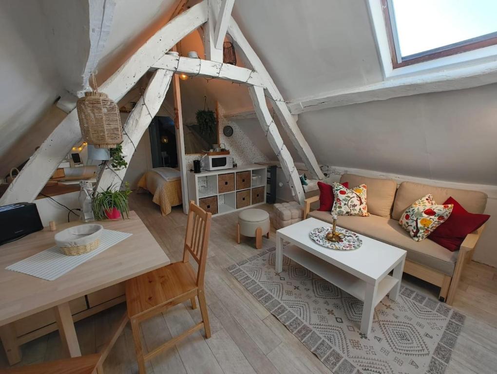 a living room with a table and a couch at Quiet Riverside Apartment in Grosley-sur-Risle