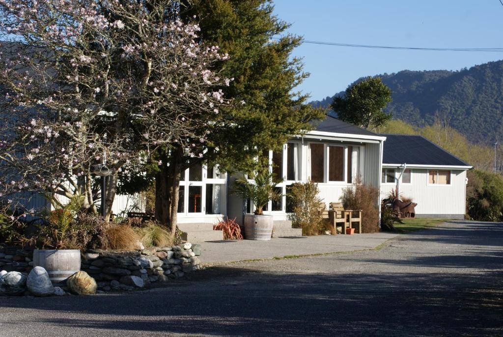 Una casa blanca con un árbol delante. en Apostles View Motel, en Greymouth