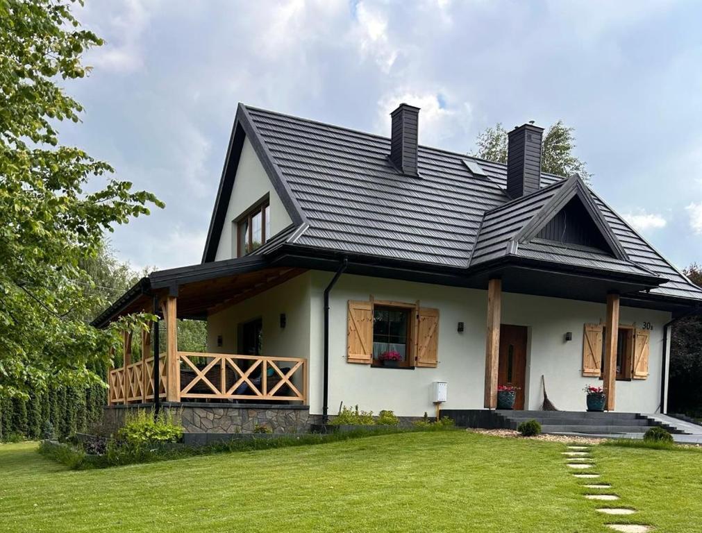 a house with a black roof and a yard at BABA JAGA na szlaku in Nowa Słupia