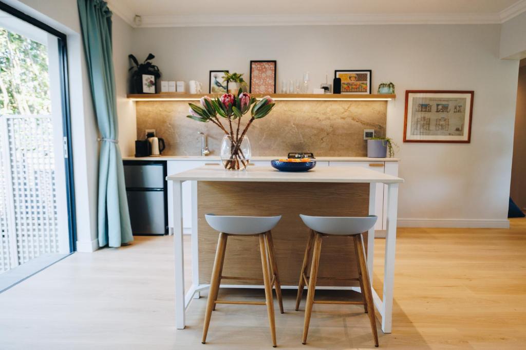 a kitchen with a white island with two stools at Suite 273 - Luxe Solar Suite - Heated Pool in Cape Town