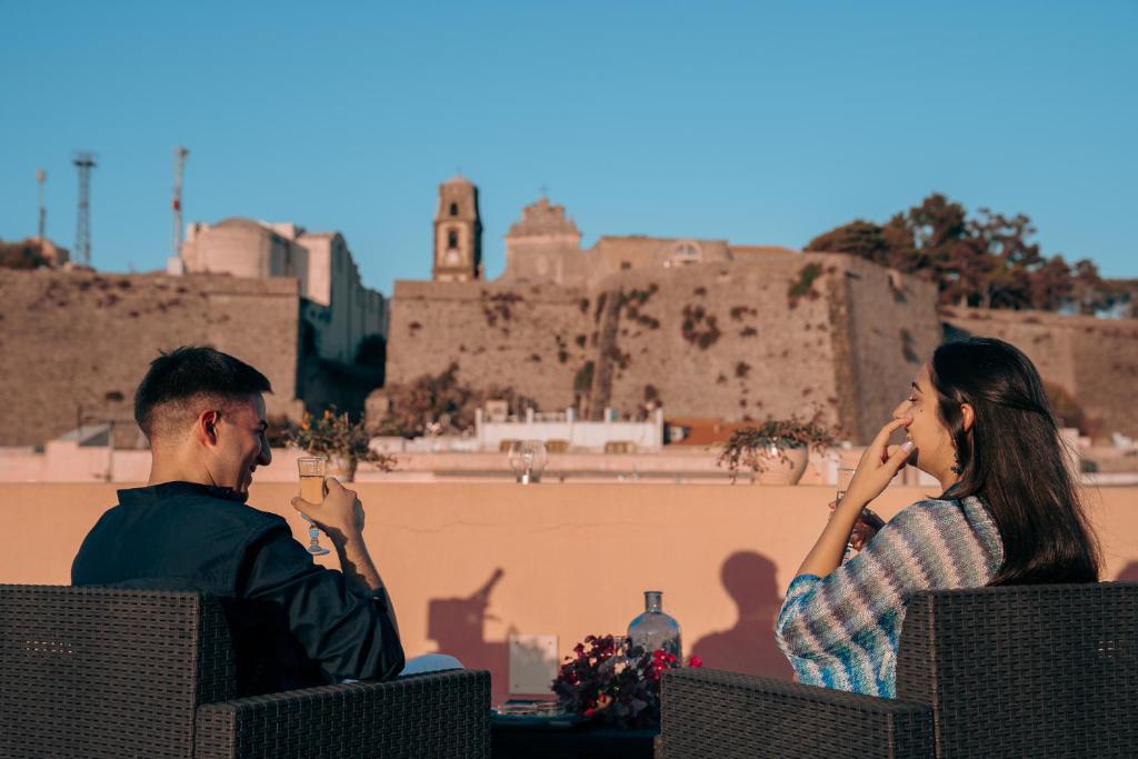 a man and a woman sitting in chairs talking on their cell phones at Residence Alberghiero Eolie in Lipari
