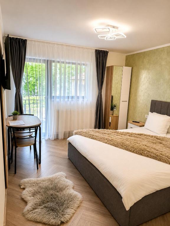 a bedroom with a bed and a table and a window at Vila Monica in Buşteni