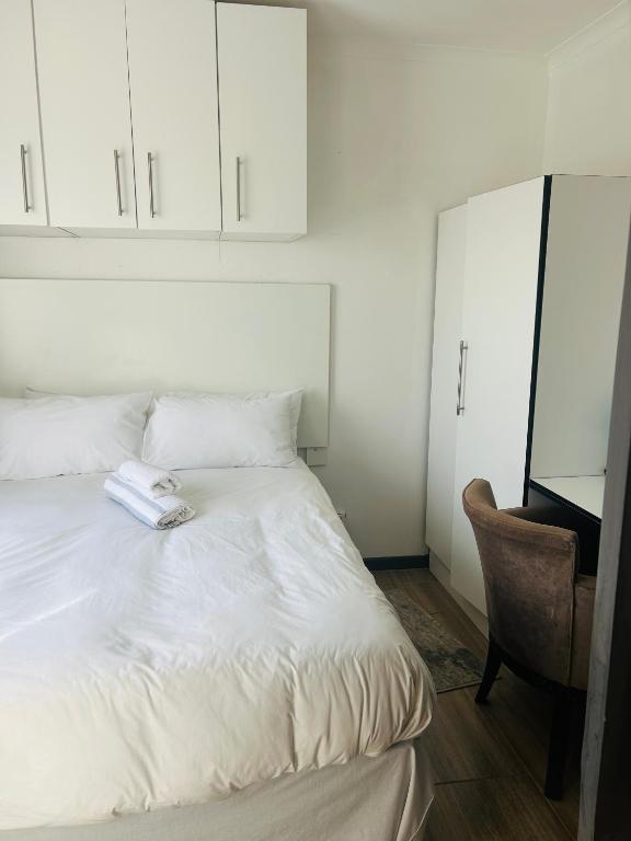 a bedroom with a white bed and a chair at Alwaba guest house in Mthatha