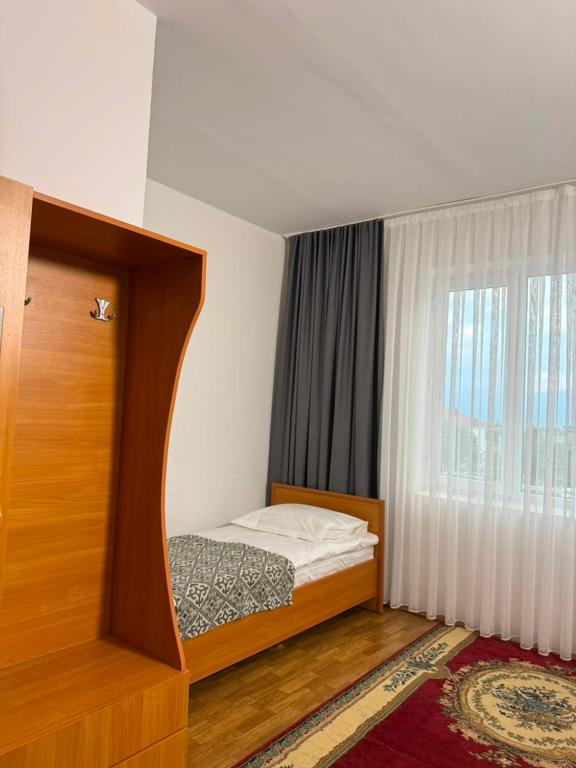 a small bedroom with a bed with a window at Barskhan Guest House in Bosteri