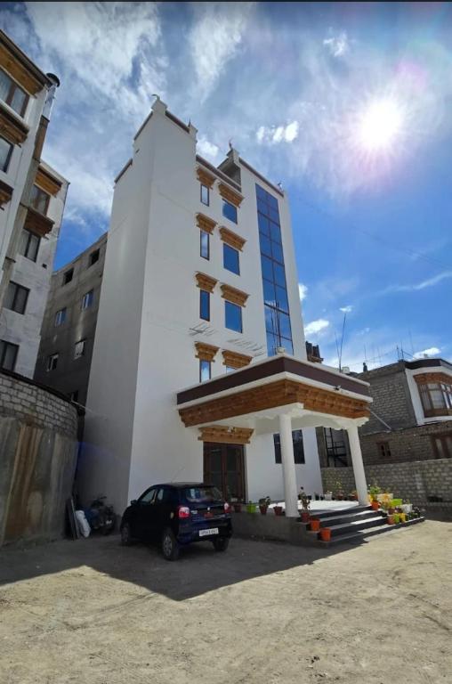 a white building with a car parked in front of it at Hotel Royal EdelWeiss in Leh