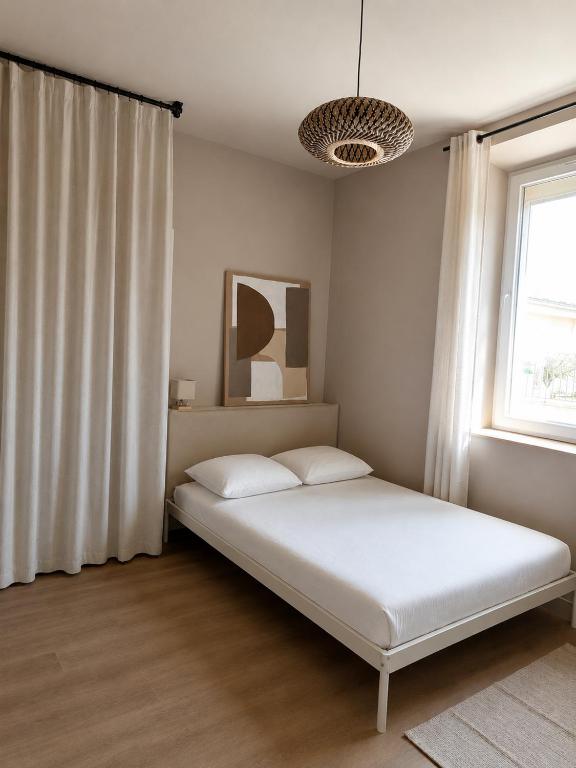 a bedroom with a bed with white sheets and a window at Le Mas d'Elio in Cheval-Blanc