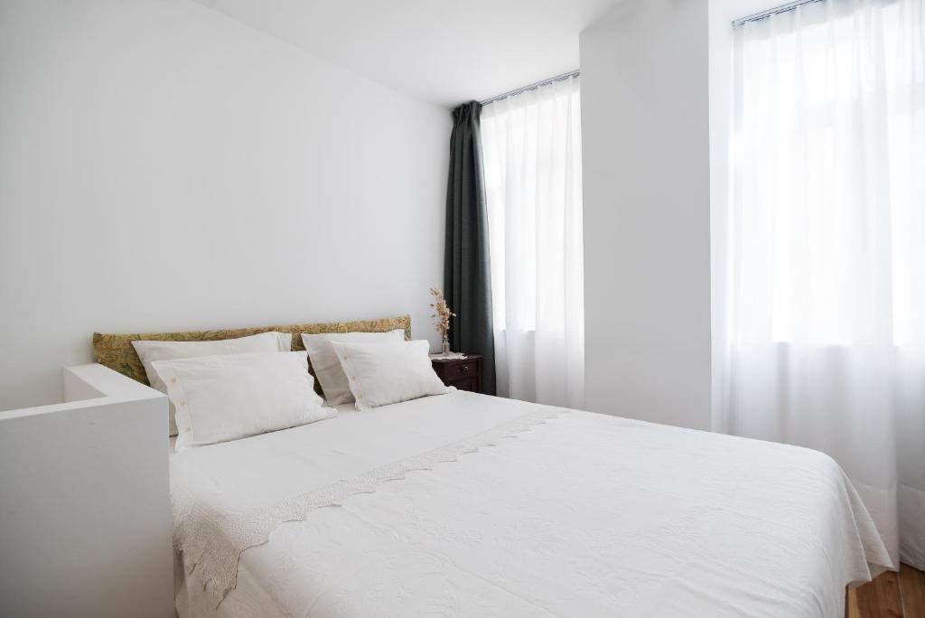 リスボンにあるLittle duplex in Alfamaの白い枕と窓が備わる白いベッド
