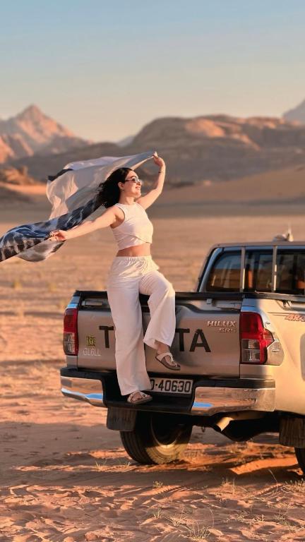 a woman standing on the back of a truck in the desert at The Martian Bubbles - Wadi Rum in Wadi Rum